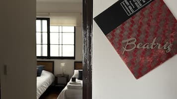 Un pasillo que conduce a un dormitorio con cama, mesita de noche y ventana.