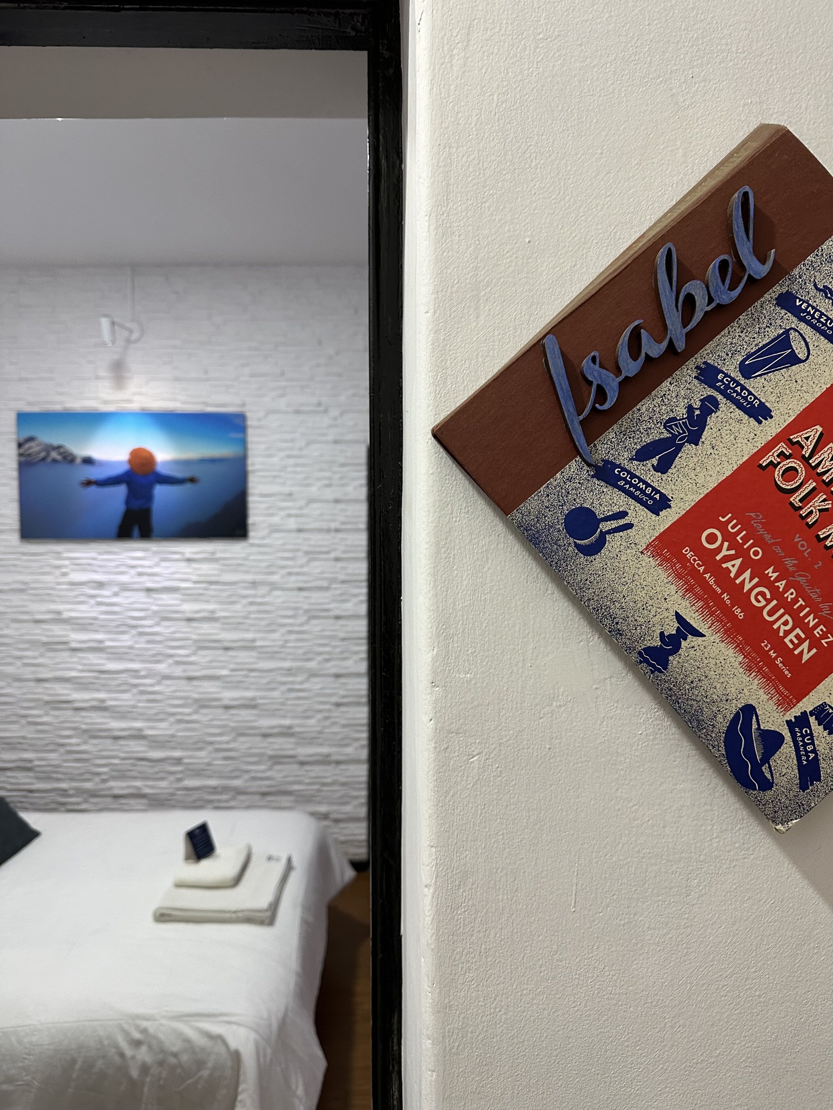 Quarto de hotel com uma cama, um quadro pendurado na parede e um cartaz.