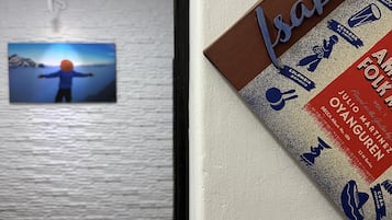 Quarto de hotel com uma cama, um quadro pendurado na parede e um cartaz.