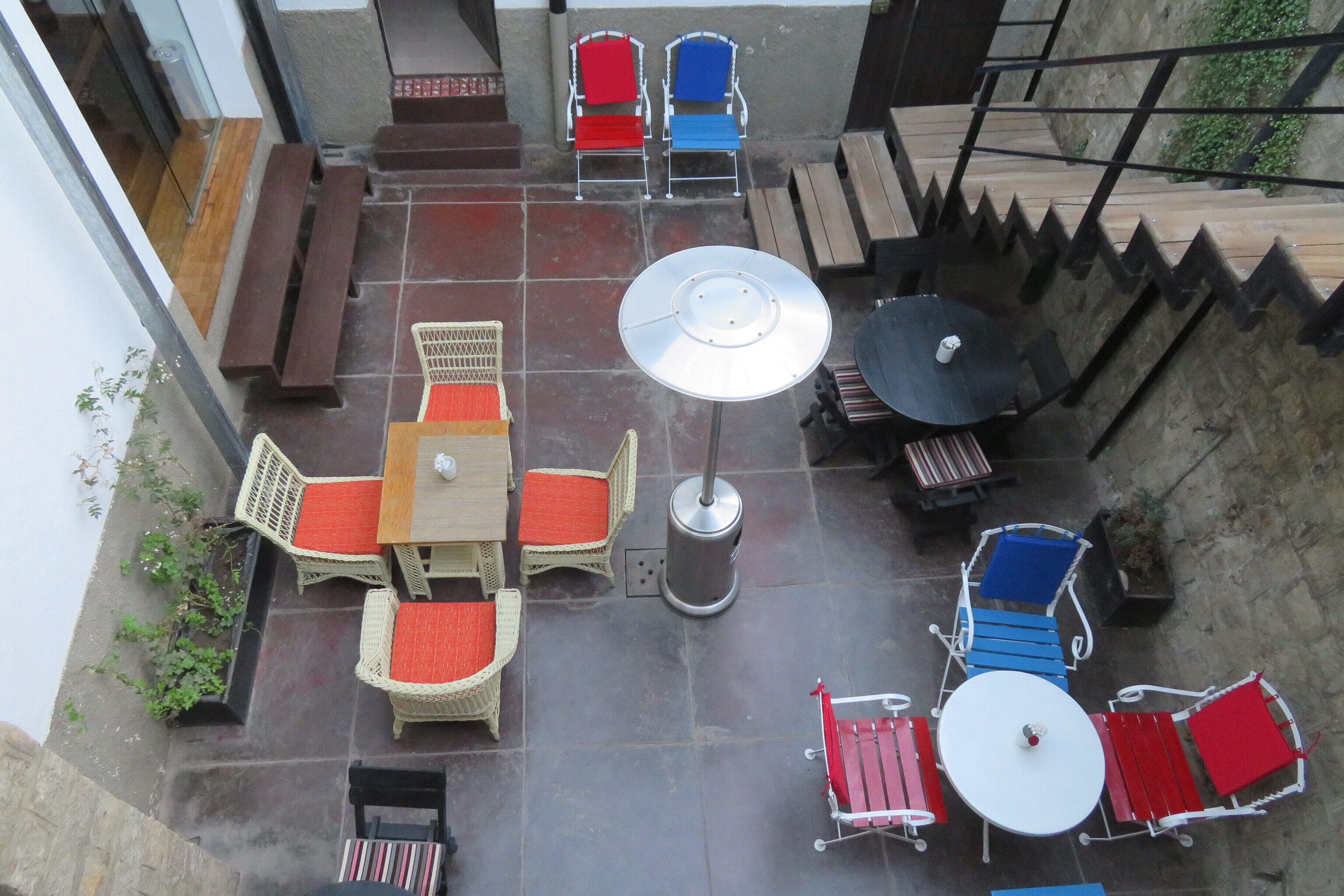 A rooftop patio with outdoor furniture, including wicker chairs and tables, and a metal umbrella.