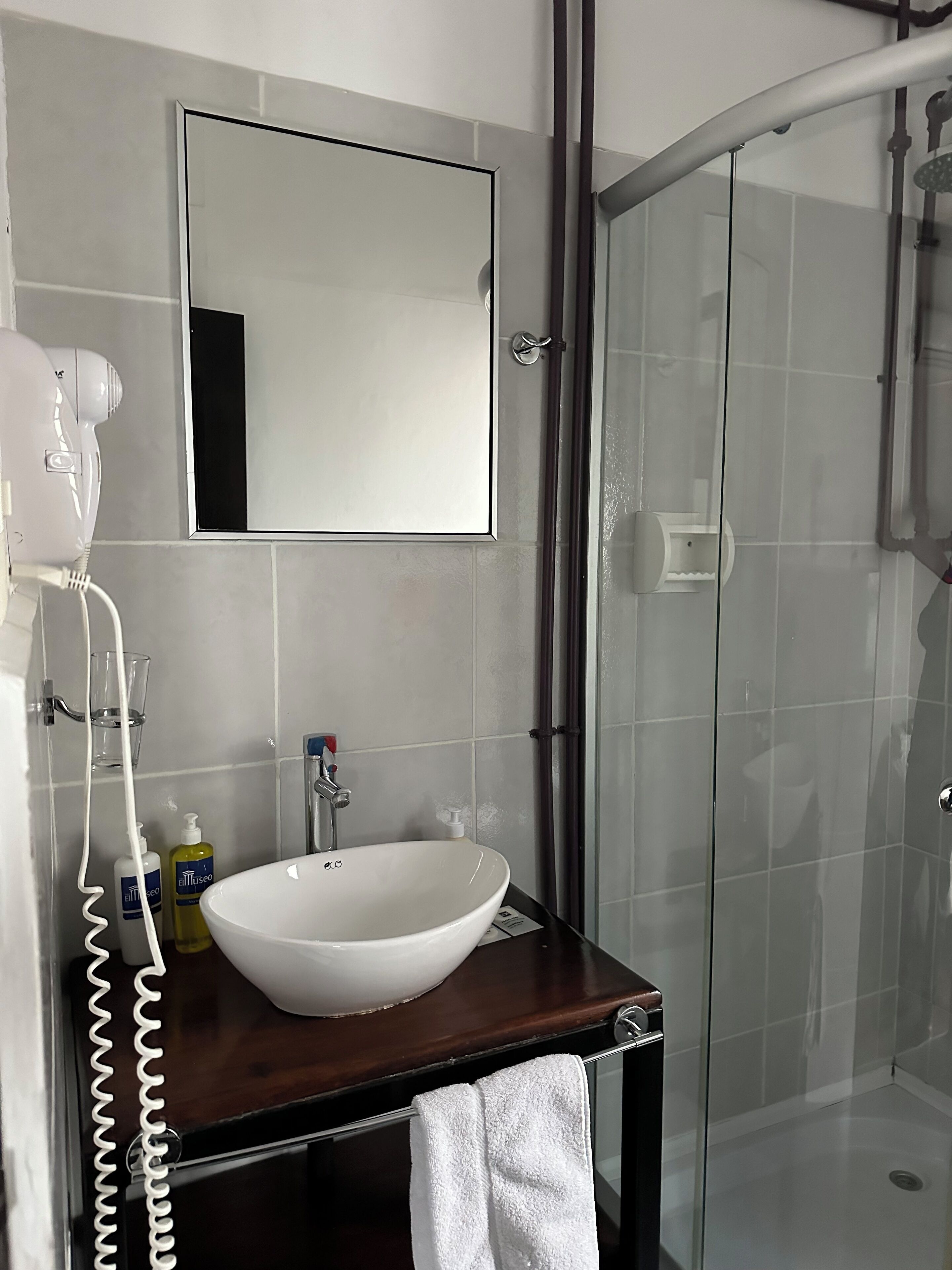 A bathroom with a white sink, a mirror, and a glass shower enclosure.
