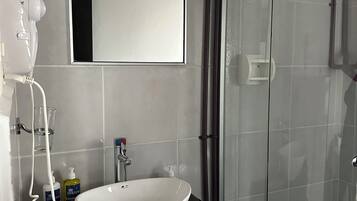 A bathroom with a white sink, a mirror, and a glass shower enclosure.