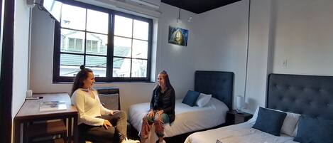 Una habitación de hotel moderna con dos camas, un escritorio y una ventana con vista a la ciudad.