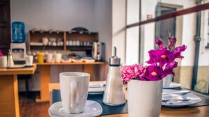 A dining table with a white cup, saucer, and a white pitcher with flowers. - El Museo Hotel Boutique (La Paz)