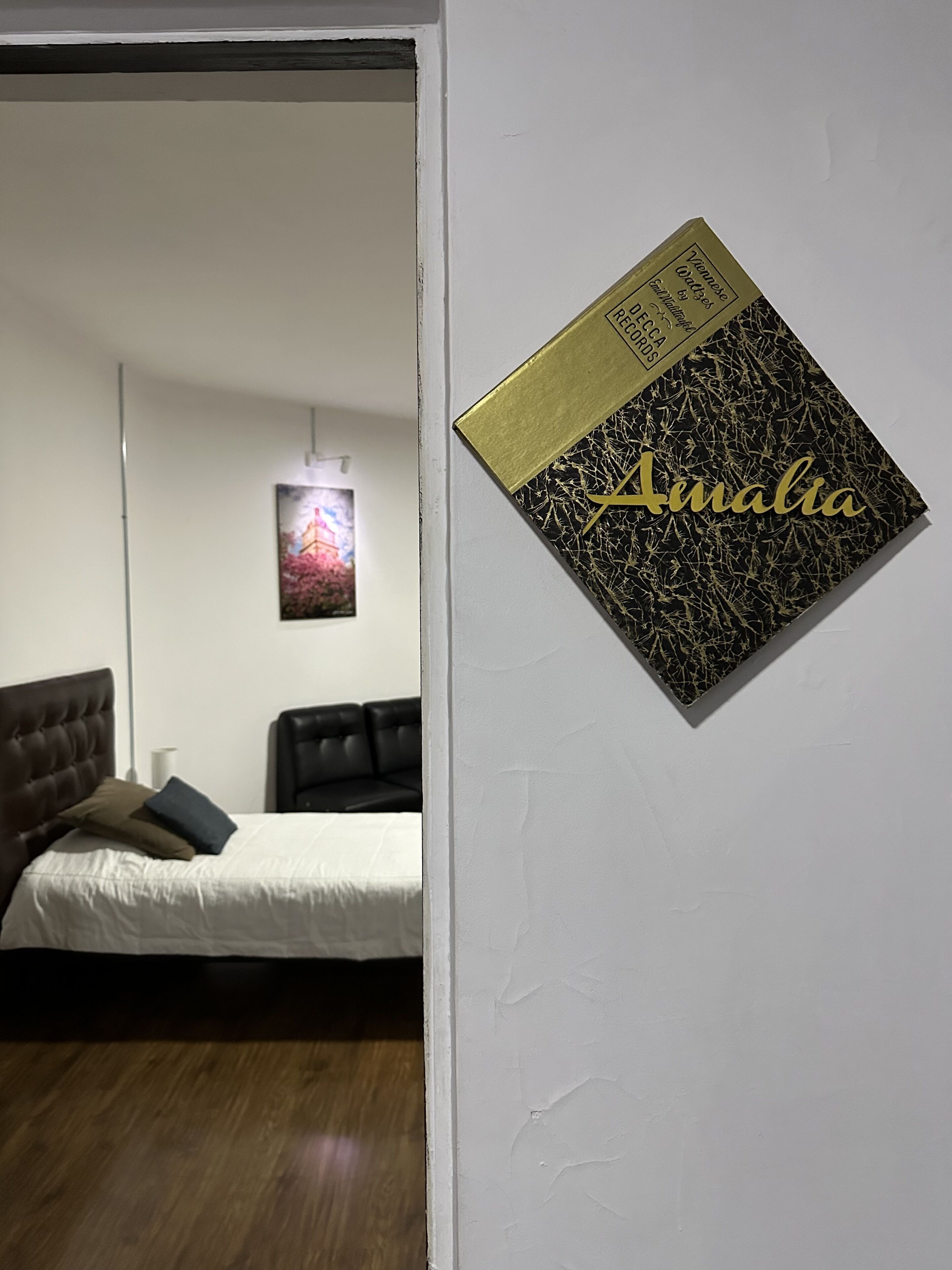 A bedroom with a bed, a headboard, and a wall-mounted artwork.