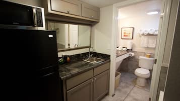 Una cocina compacta con un refrigerador negro, un lavamanos y un microondas.