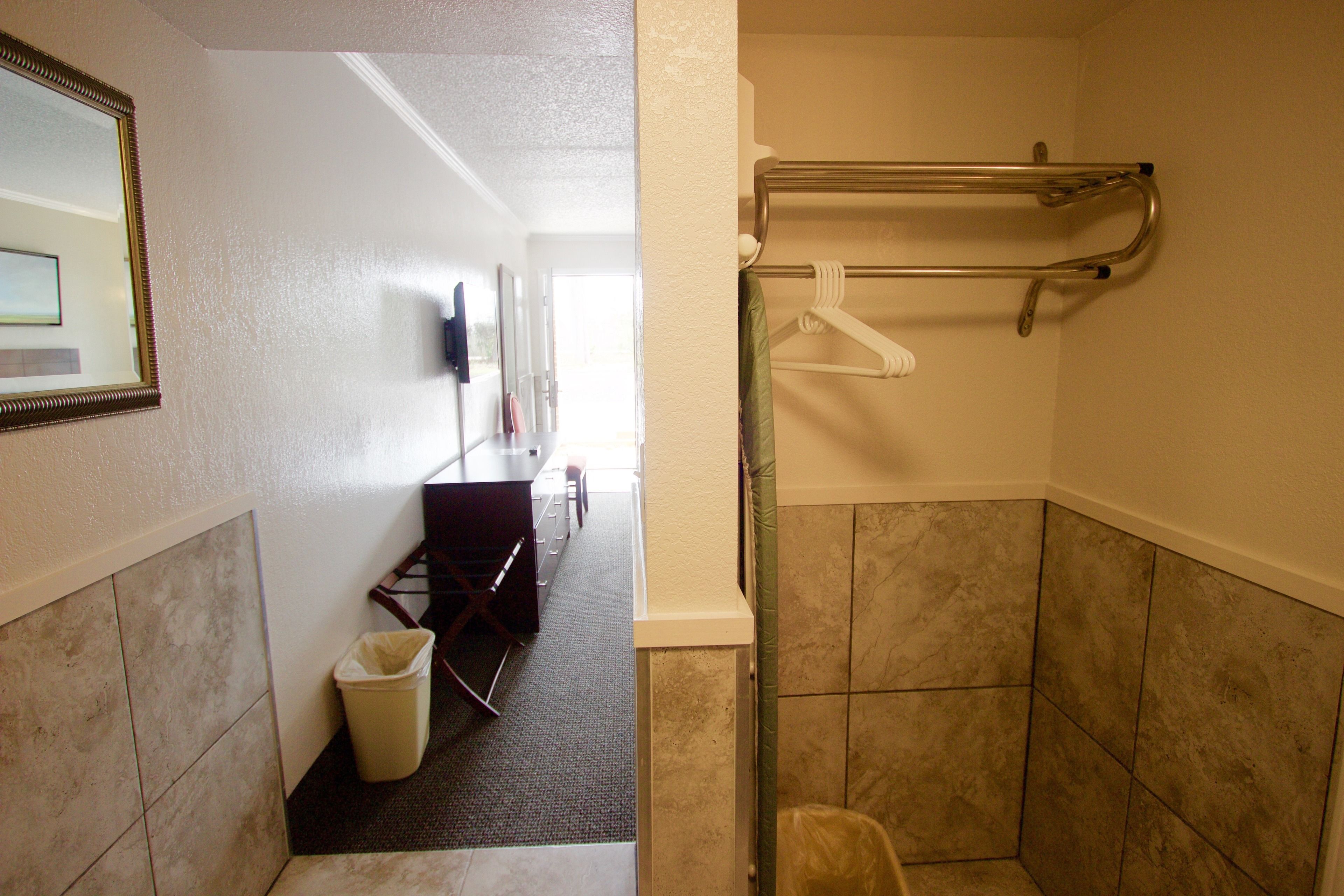 Un baño de hotel con ducha, un perchero para toallas, un cesto de basura y un espejo.