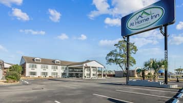 Un hotel con cielo despejado, estacionamiento y un letrero que dice 'At Home Inn Pensacola'.