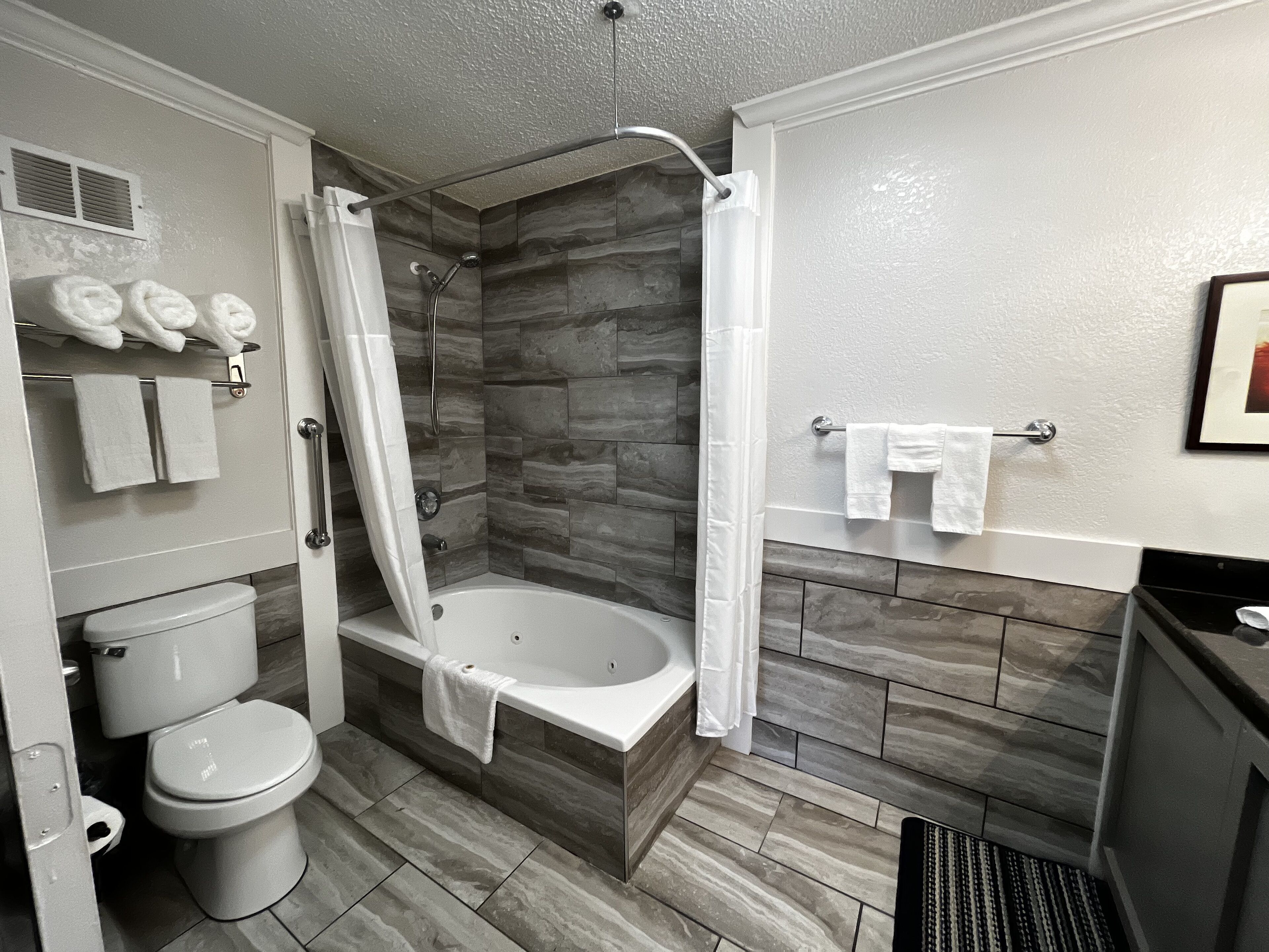 A modern bathroom with a bathtub, shower, toilet, and towel rack.