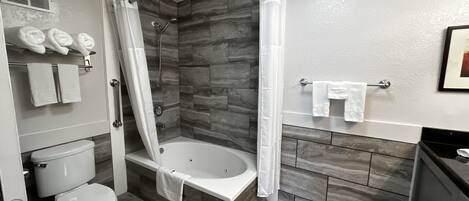 A modern bathroom with a bathtub, shower, toilet, and towel rack.