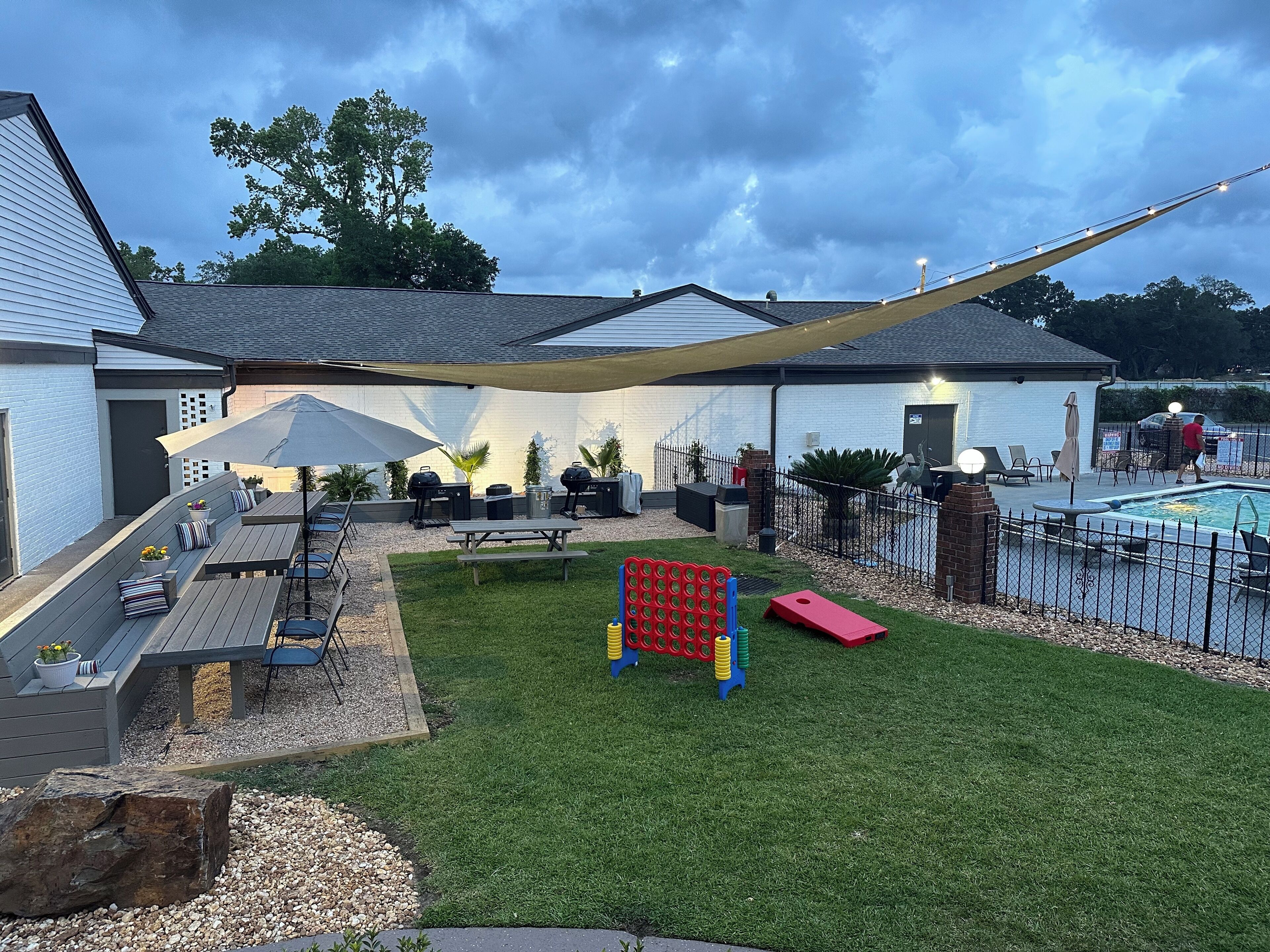 A backyard with a pool, patio furniture, a hammock, and a play area.