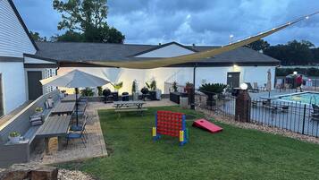 A backyard with a pool, patio furniture, a hammock, and a play area.