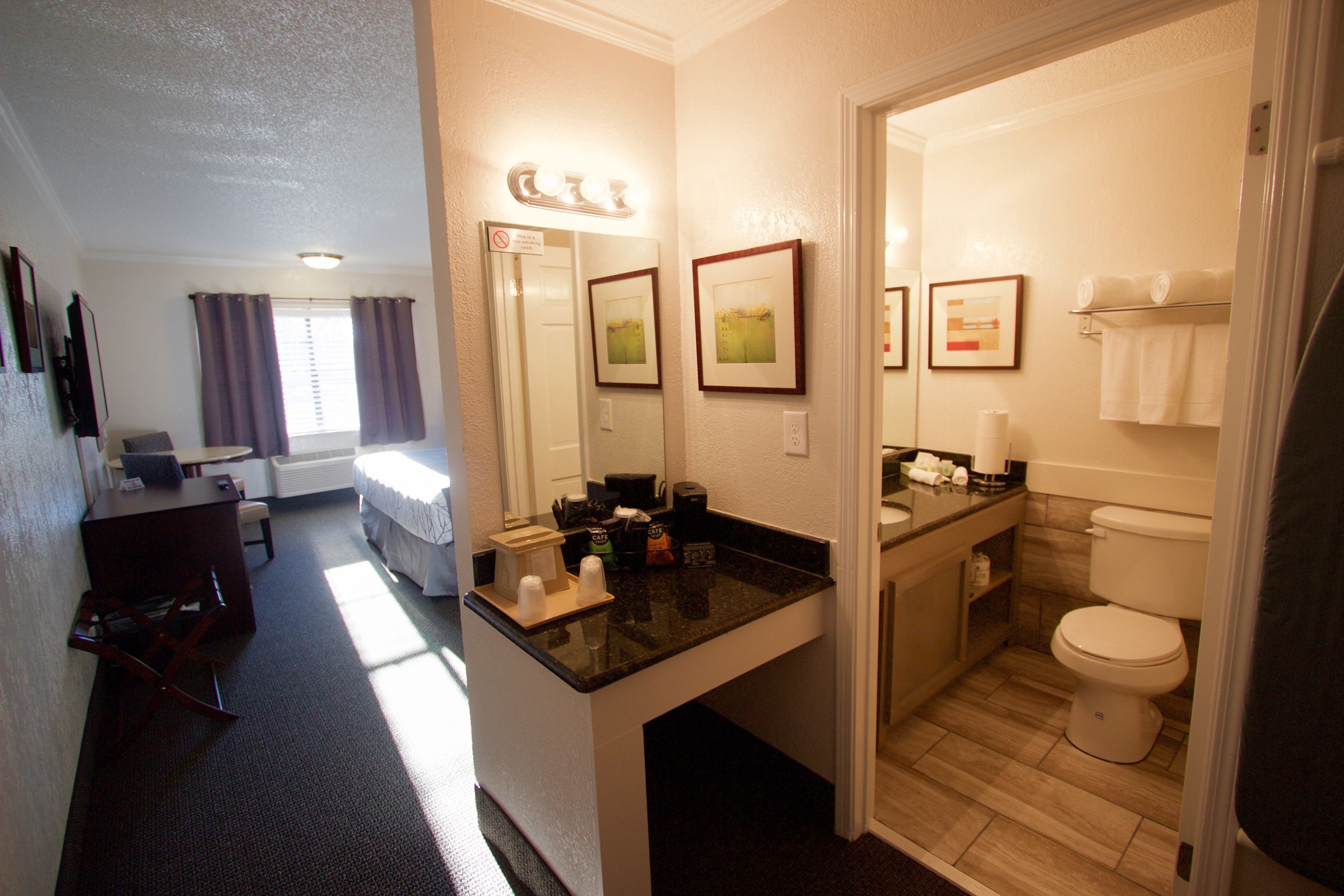 A hotel room with a bed, a desk, a bathroom with a toilet, and a shower area.