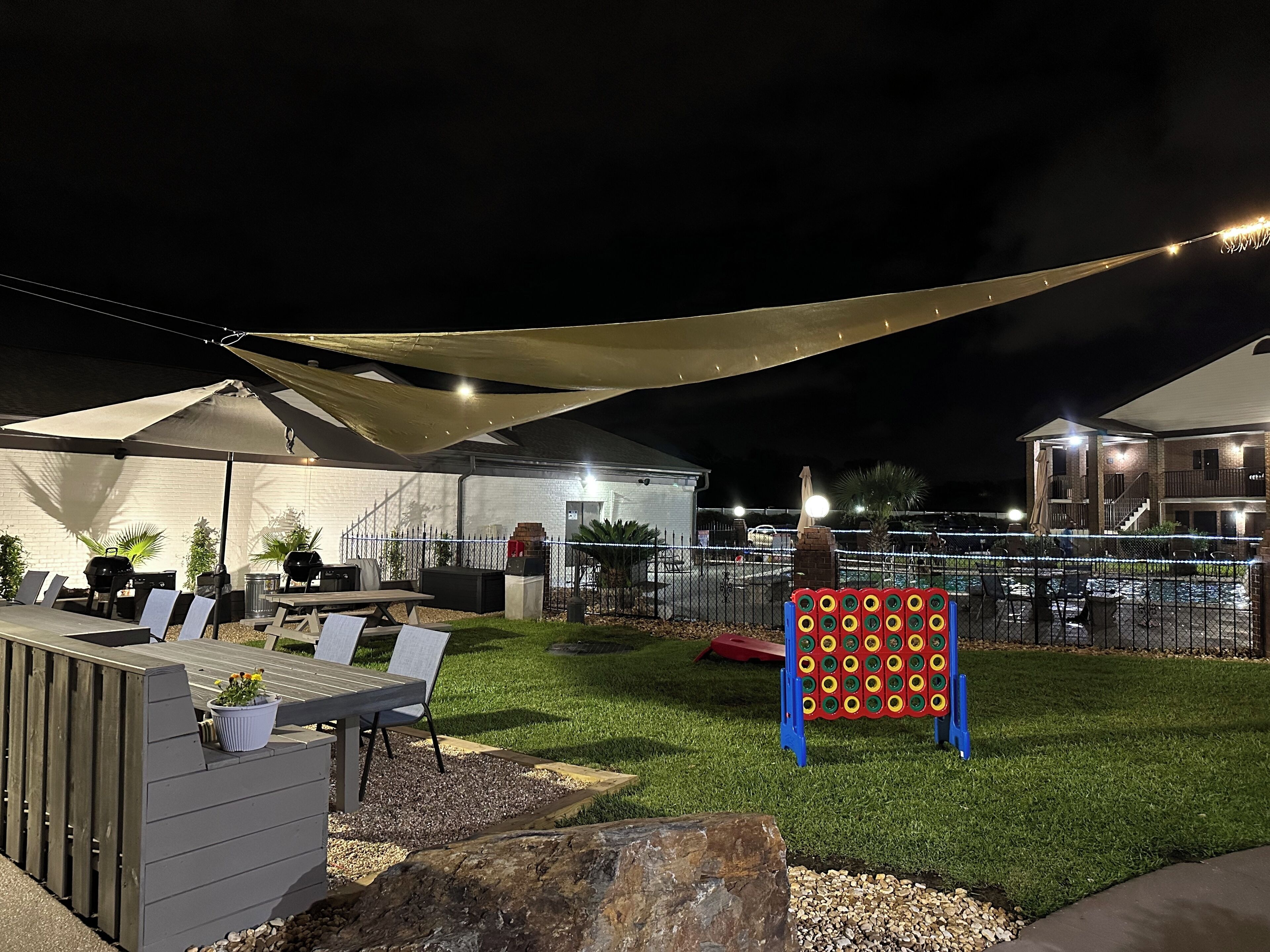 An outdoor patio area with a table and chairs, a barbecue grill, and a decorative board.