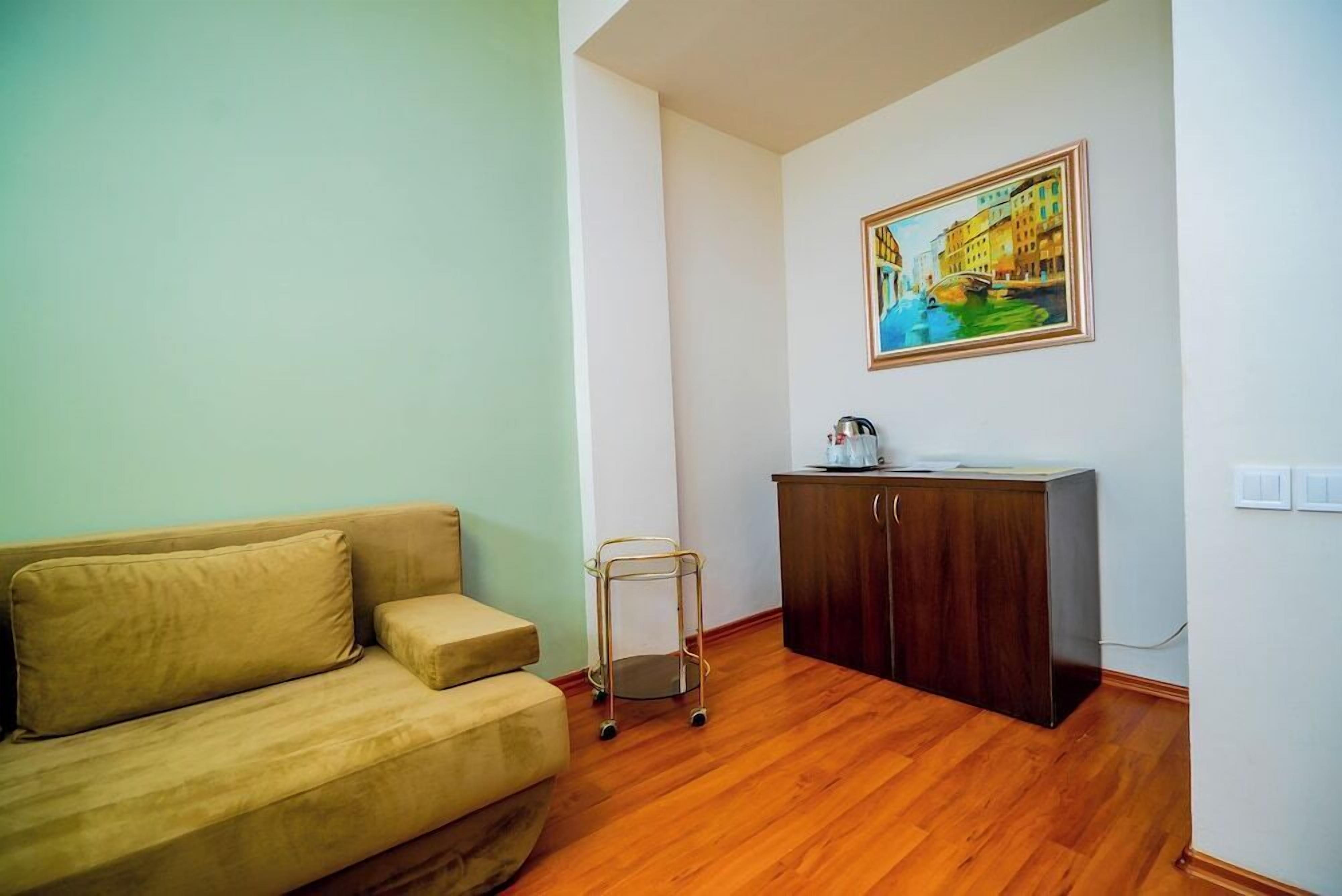 Una sala de estar con un sofá, un mueble pequeño y un cuadro en la pared.
