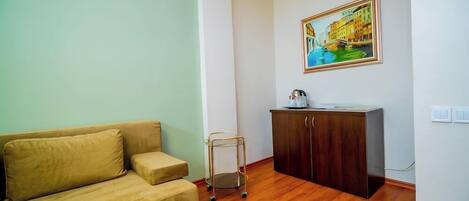 Una sala de estar con un sofá, un mueble pequeño y un cuadro en la pared.
