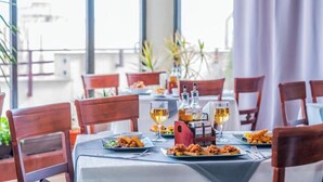 Una mesa de comedor servida con platos de comida, copas de vino y una botella de salsa.