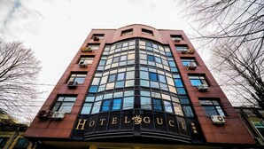 Un hotel con fachada curva, múltiples unidades de aire acondicionado y un letrero llamativo con el nombre 'HOTEL GUCCI'.