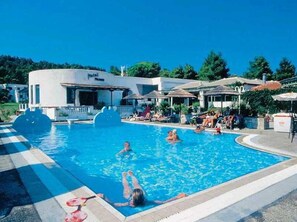 A swimming pool area with a hotel building in the background, surrounded by greenery. - Muses (Skiathos)