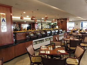 Un restaurante con una barra de buffet, mesas y sillas.