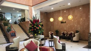 A lobby with a reception desk, seating area, staircase, and a decorative floral arrangement. - Hotel Grand Continental Kuala Terengganu (Kuala Terengganu)