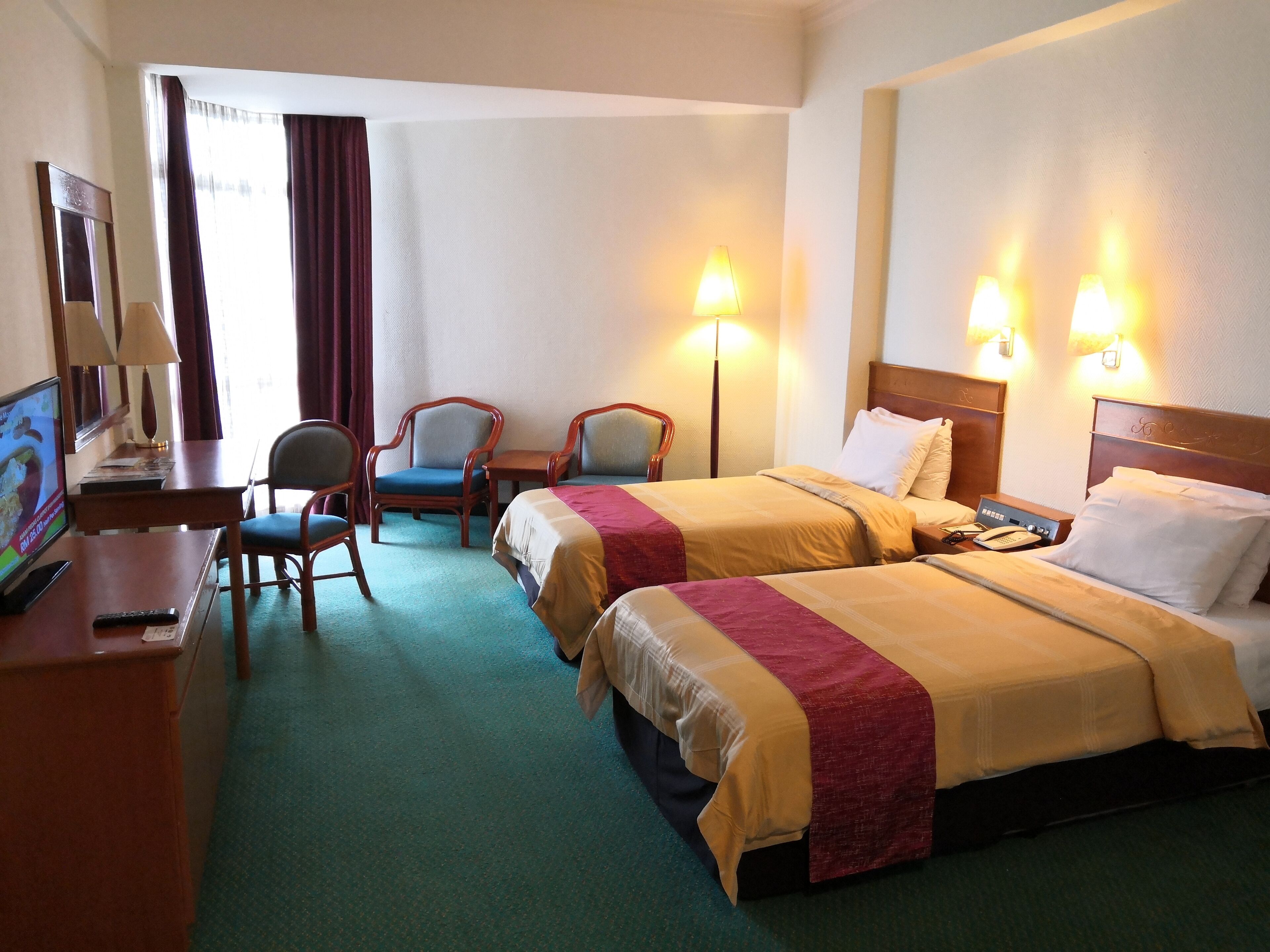 Habitación de hotel con dos camas, un escritorio con computadora, una silla y televisión.