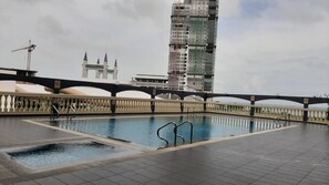 Piscina en la azotea con vista a un edificio alto en construcción.