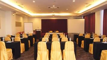 A conference room with rows of tables and chairs, a podium, and a projection screen.
