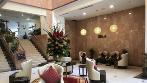 A lobby with a reception desk, seating area, and a staircase.