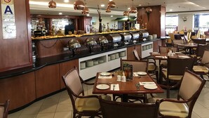 A restaurant with a buffet counter, dining tables, and chairs.