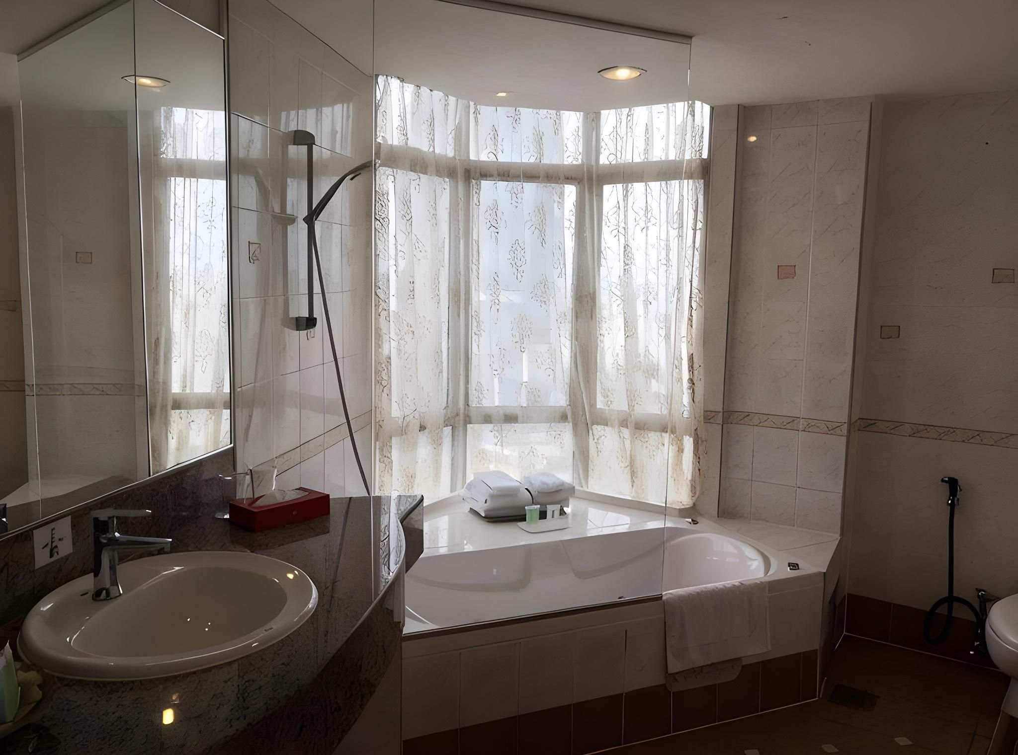 Un baño moderno con un espejo grande, un lavamanos, una bañera y una ducha.