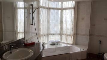 Un baño moderno con un espejo grande, un lavamanos, una bañera y una ducha.
