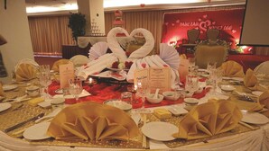 A formal dining setup with white and gold table settings, a heart-shaped centerpiece, and a red backdrop with the names "Paul Lau" and "Nick Lee".