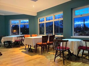 A dining area with tables and chairs, large windows, and a view of the outside. - Panmure Arms (Brechin)