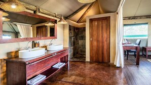 A rustic bathroom with a wooden vanity, two sinks, a large mirror, and a shower area. - Eagle Tented Lodge (Okaukuejo)