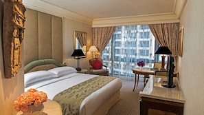 A hotel room with a large bed, two bedside tables, a desk, a chair, a window with curtains, and a view of a building.