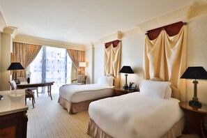 A hotel room with two beds, a desk, a chair, and a view of the city. - Intercontinental Phoenicia Beirut (Beirut)