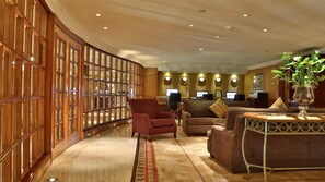 A lobby with a curved wooden partition, seating area with sofas and armchairs, and a desk with computers. - Intercontinental Phoenicia Beirut (Beirut)