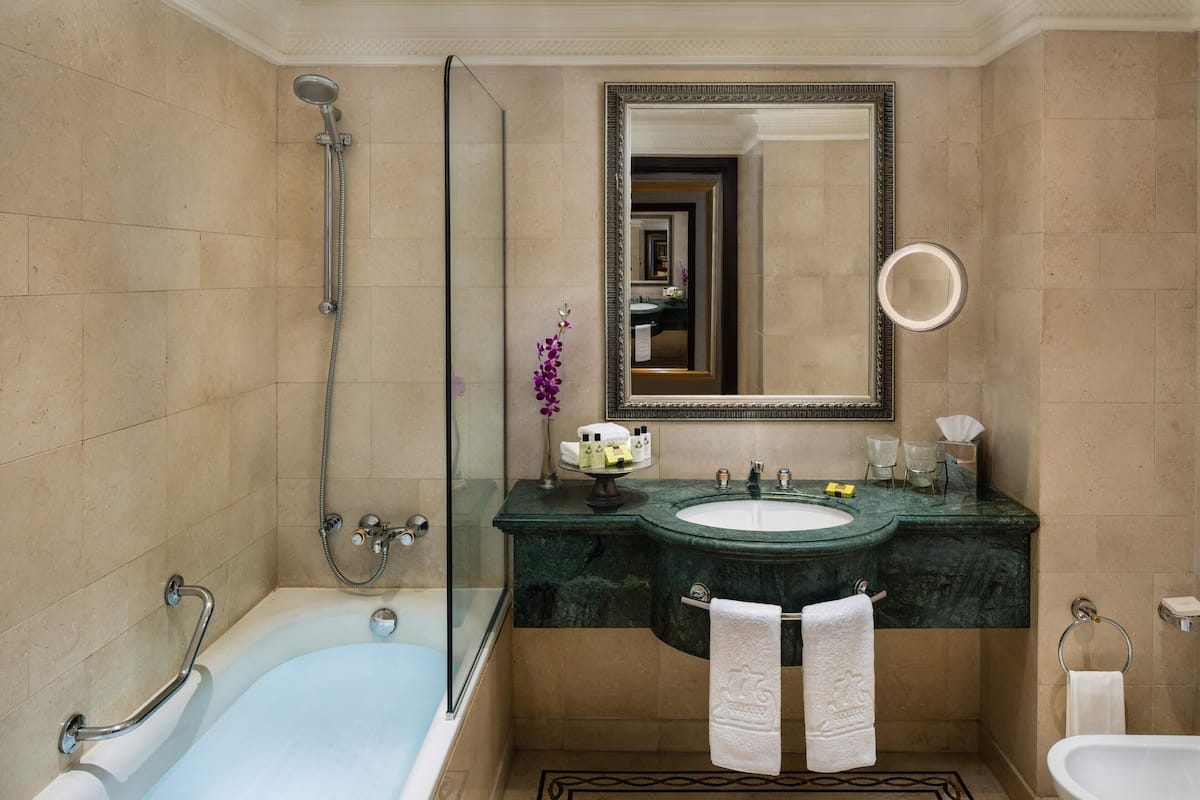 A bathroom with a bathtub, a shower, a sink with a mirror, and a toilet.