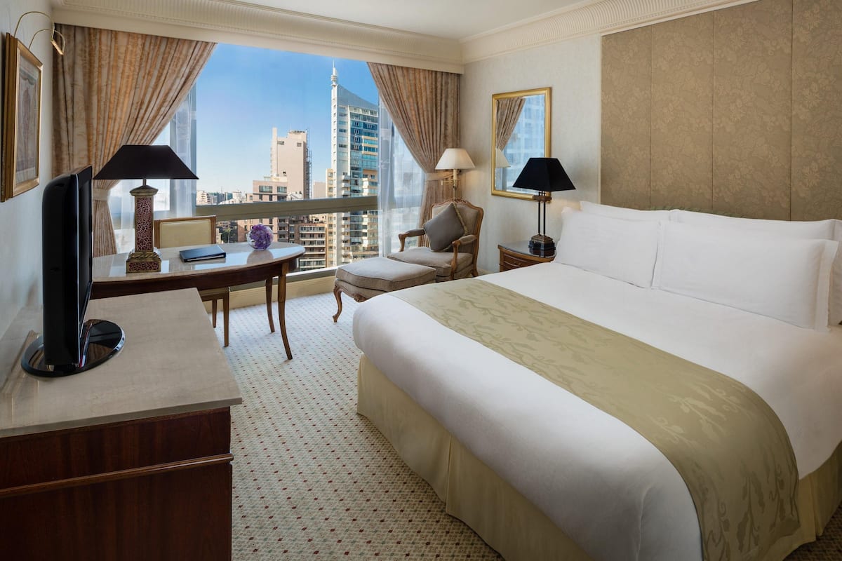 Una habitació d'hotel amb un llit gran, un escriptori, una cadira i vista a la ciutat.