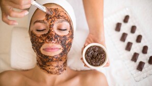 Una persona recibiendo un tratamiento facial con una mascarilla y un cuenco con una sustancia marrón.