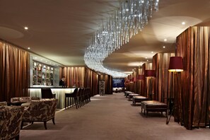 A bar area with a long counter, chairs, and a chandelier. - Intercontinental Phoenicia Beirut (Beirut)