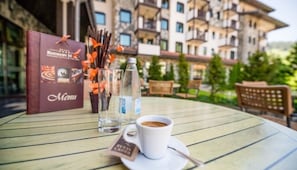 A table with a menu, a cup of coffee, and a bottle of water. - Rhodopi Home (Chepelare)