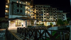 A multi-story hotel with illuminated balconies and a well-lit entrance. - Rhodopi Home (Chepelare)