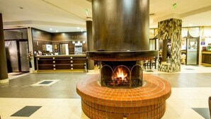 A lobby with a central fireplace, a reception desk, and a seating area.