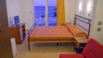 Un dormitorio con cama, escritorio, silla, televisor y vista al mar.