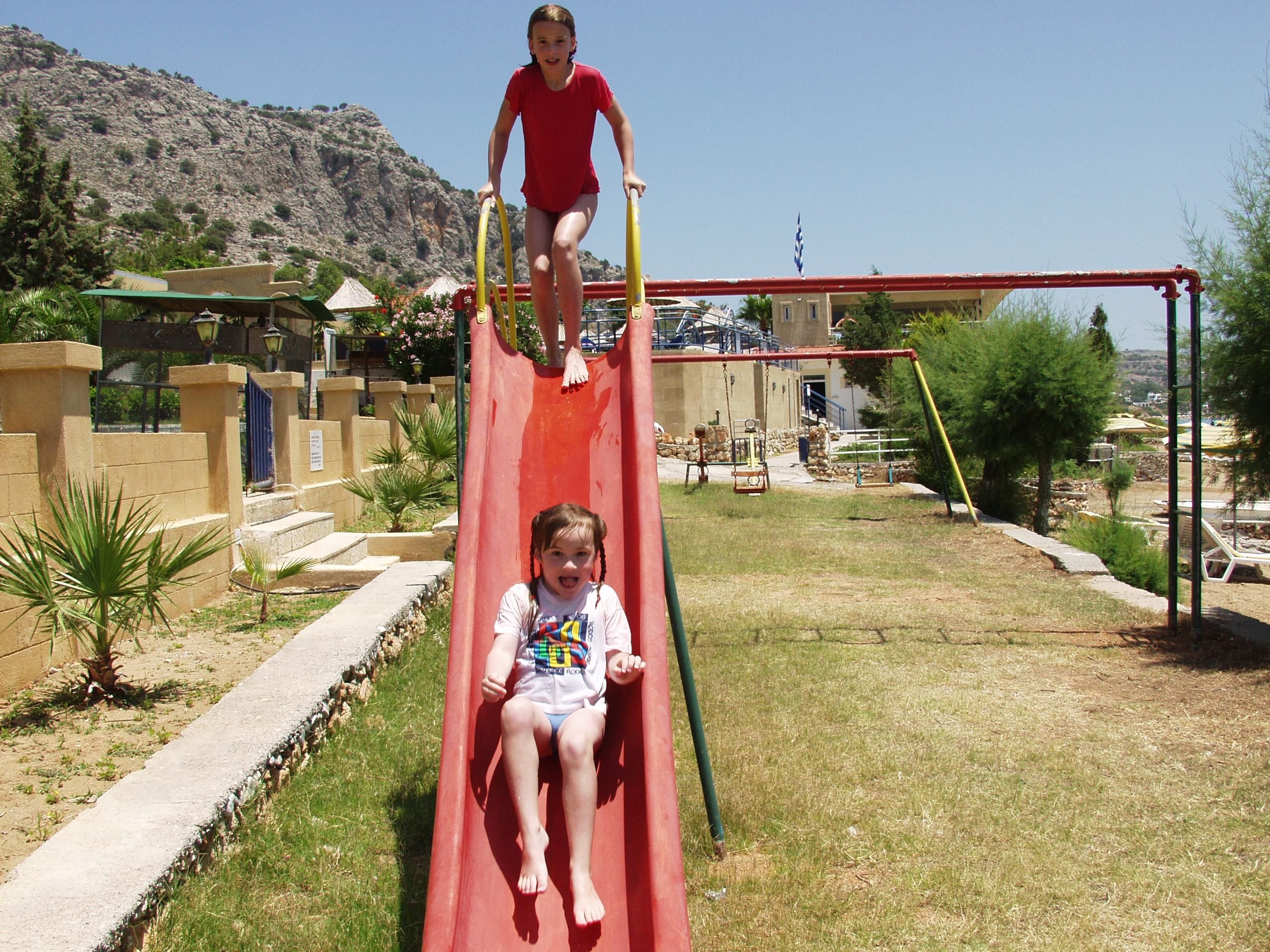 Un parque infantil con un tobogán rojo y una estructura para escalar.