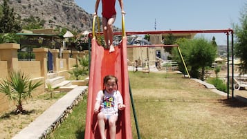 Un parque infantil con un tobogán rojo y una estructura para escalar.