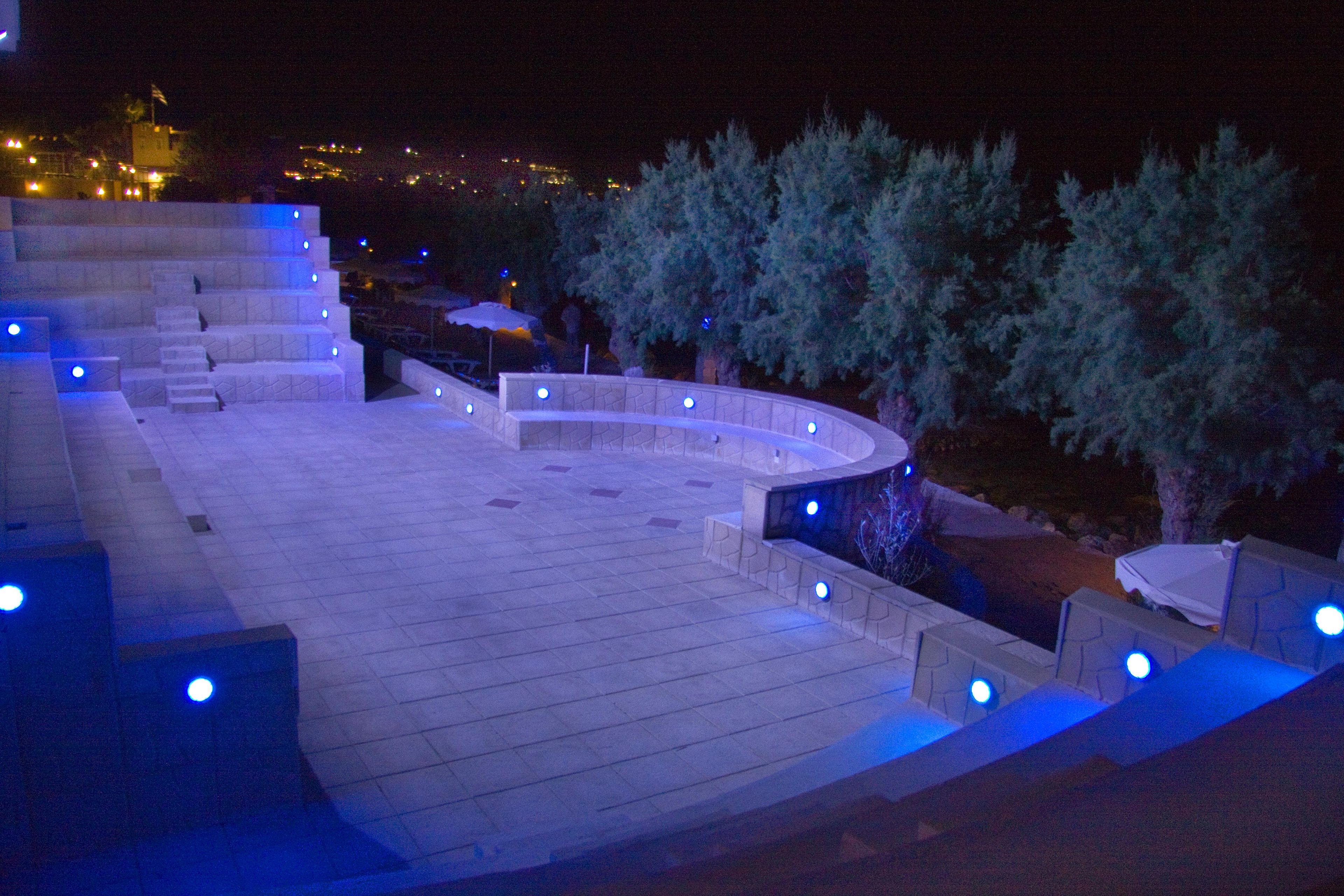 Espacio al aire libre de noche con una distribución de asientos curvada y escalones que lo conducen.