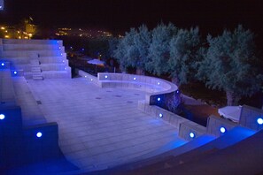 Un espace extérieur aménagé pour la nuit, avec des sièges disposés en arc de cercle et des marches menant à cet espace.